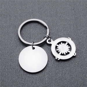 Porte-clés boussole en acier inoxydable avec disque en métal sur fond gris texturé
