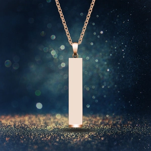 Rose gold rectangular bar necklace with minimalist 3D geometric pendant on bokeh background