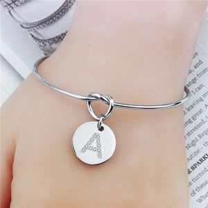 Gros plan d'un bracelet à nœud argenté avec pendentif lettre A serti de cristaux