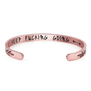Close-up of rose gold cuff bracelet with KEEP FUCKING GOING inspirational engraving