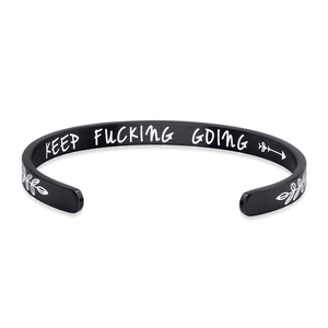 Macro view of matte black stainless steel C-shape cuff with engraved motivational text