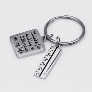 Detailed macro view of stainless steel ruler keychain with engraved inspirational quote