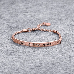 Gros plan du bracelet en titane or rose avec plaque incurvée gravée Keep Fucking Going