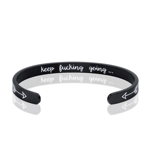 Macro detail of engraved inner band on black matte stainless steel C-shaped cuff bracelet