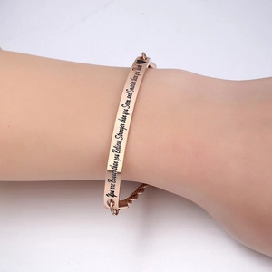 Détail d'un bracelet jonc en or rose avec gravure inspirante et petit motif de cœur