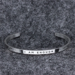 Close-up of polished silver metal cuff bracelet featuring I AM ENOUGH engraving