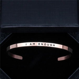 Detailed macro view of I AM ENOUGH engraving on a rose gold stainless steel cuff