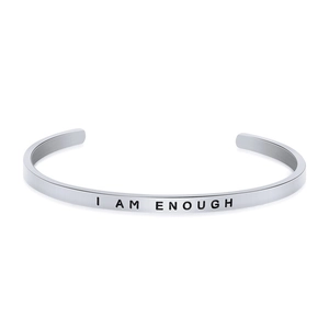 Detailed view of silver C-shaped cuff bracelet engraved with I AM ENOUGH text