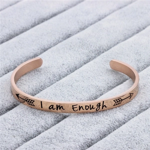 Dettaglio dell'incisione I am enough sul bracciale rigido piatto in acciaio oro rosa