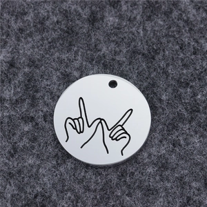 Macro detail of round stainless steel pendant with engraved hand gesture on felt