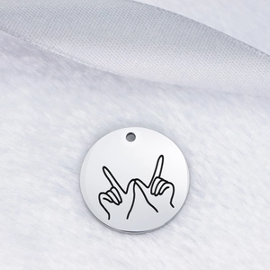 Polished stainless steel round pendant with black laser engraved hand gesture on white fur
