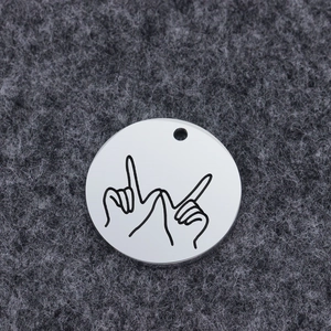 Polished stainless steel round pendant with hand gesture engraving on gray felt background