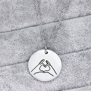 Macro di una collana in acciaio al titanio argento con ciondolo a cuore con le mani