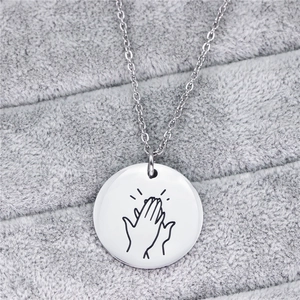 Macro di collana in acciaio al titanio argento con mani incise su vassoio in velluto grigio