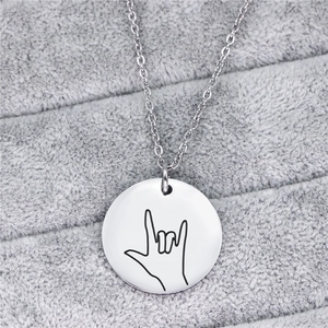 Dettaglio della collana con ciondolo tondo argento e segno I Love You su peluche