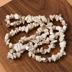 Close-up of irregular white howlite stone beads with brown marble texture on wood
