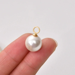 18K gold-plated copper pearl pendant with bail connector held in fingers for jewelry DIY