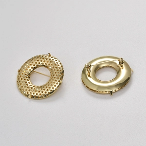 Détail macro de la broche ronde dorée 38mm avec motif nid d'abeille ajouré et épingle au dos