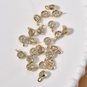 Detail of 14k gold plated flower pendants with rhinestones on a white ceramic tray