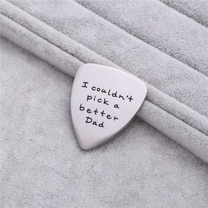 Macro detail of brushed stainless steel guitar pick with father's day engraving