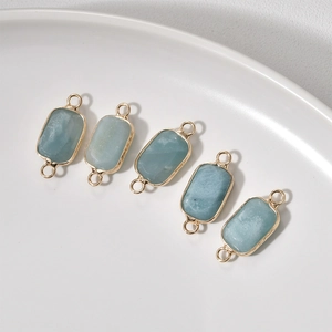 Detail of light blue rectangle crystal pendants with gold plated edges on ceramic tray