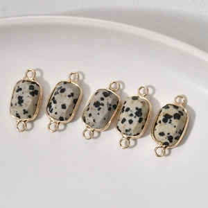 Macro detail of rectangle dalmatian stone connectors with gold plated borders for jewelry