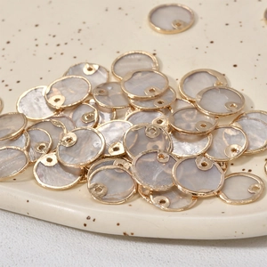 Gros plan de pendentifs ronds en nacre avec bords dorés pour la création de bijoux DIY