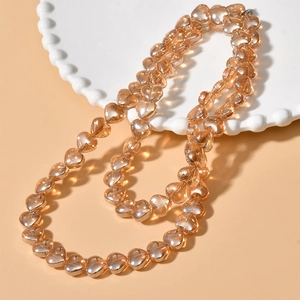 Close-up of amber heart-shaped glass beads on a white decorative porcelain plate