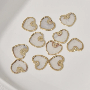Gros plan de pendentifs en nacre en forme de cœur avec bords dorés pour la création bijoux