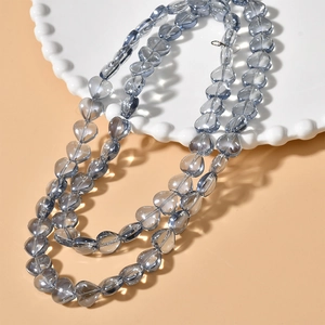 Detailed view of heart-shaped blue glass beads on a white plate for DIY jewelry making