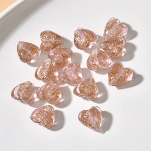 Macro shot of pink heart-shaped glass beads with gold glitter for DIY jewelry making