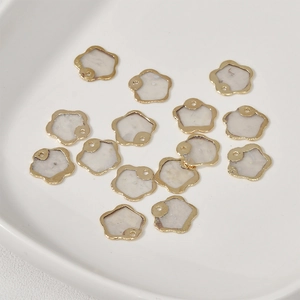 Vue macro de pendentifs fleurs dorés avec pétales en coquillage blanc pour bijoux DIY
