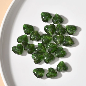 Close-up of green heart-shaped glass beads with gold glitter for DIY jewelry making