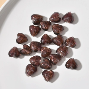 Detail of dark purple heart glass beads with gold sand shimmer for DIY jewelry making