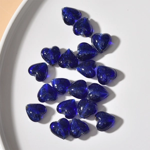 Macro detail of blue heart-shaped glass beads with gold sand glitter for DIY jewelry
