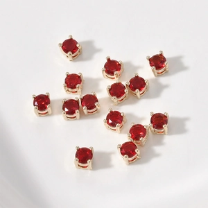 Primer plano de cuentas redondas de circón rojo con engastes dorados de cuatro garras para bricolaje