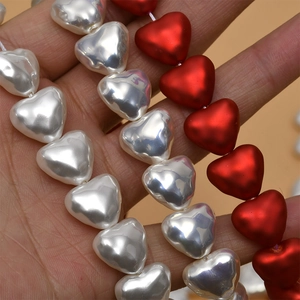 Close-up of heart-shaped faux pearl and matte red beads for DIY jewelry making