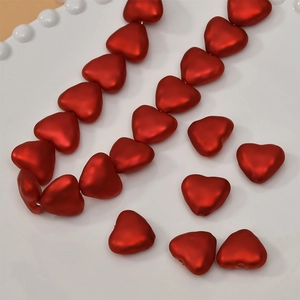 DIY jewelry kit with matte red heart-shaped pearls on a white ceramic plate for accessories
