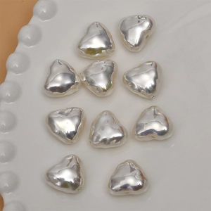 Close-up of heart-shaped silver metallic beads on a white tray for jewelry DIY