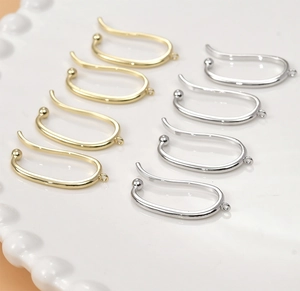 Macro shot of 14k gold and silver U-shaped ear clip components for DIY jewelry making