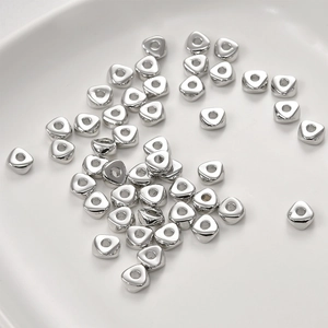 Gros plan de perles d'espacement triangulaires en métal pour bijoux DIY sur plateau