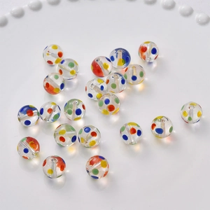 Close-up of clear glass beads with colorful dots for DIY jewelry making