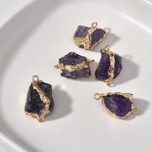Nahaufnahme von fünf Amethyst-Anhängern mit Goldrand in einer weißen Keramikschale