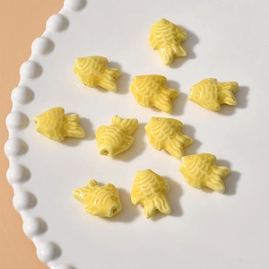 Macro shot of bright yellow ceramic fish beads with glazed finish for DIY jewelry