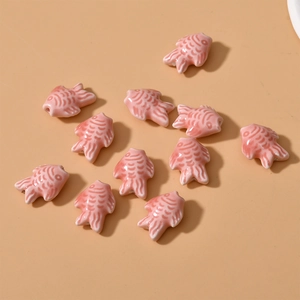 Close-up of pink ceramic fish-shaped beads with glossy glaze for DIY jewelry making