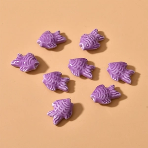 Macro shot of 8 purple fish-shaped ceramic beads with smooth glaze and detailed scales