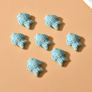 Macro view of light blue ceramic fish beads with glazed finish and fine scale textures