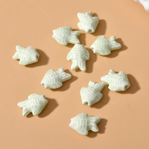 Macro shot of light green ceramic fish beads with textured scales for DIY jewelry making