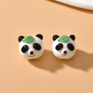 Detail of handmade panda glass beads with green leaf accents for DIY jewelry making