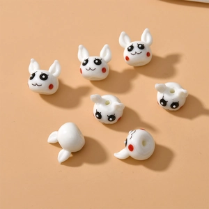 Macro view of cute white ceramic bunny beads with smiling faces for DIY jewelry making